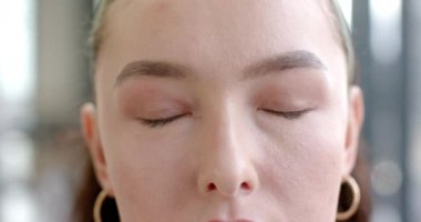 Mavi gözlü, halka küpeli ve kameraya bakan kadının yakın çekimi. Güzellik, portre, moda, mücevher, makyaj, tarz