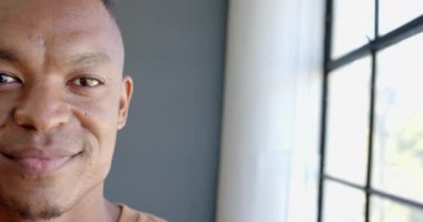 Ofisteki pencerenin yanında duran gülümseyen Afrikalı Amerikalı adam doğal ışığın tadını çıkarıyor, fotokopi çekiyor. İş, işyeri, profesyonel, kurumsal, mutluluk, rahatlama