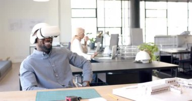 VR kulaklığı kullanarak, ofisteki adam sanal çevreyle etkileşimde, gülümsüyor. Teknoloji, sanal gerçeklik, işyeri, yenilik, iş dünyası, dijital