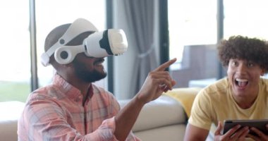 VR kulaklığı kullanan bir adam elinde tabletle sanal gerçeklik deneyiminin tadını çıkarıyor. Teknoloji, eğlence, oyun, arkadaşlık, etkileşim, modern