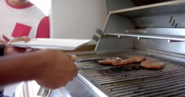 Barbekü ızgarasında hamburgerleri ızgara köfte yapmak için maşa kullanan biri. Yaz, yemek, açık hava, yemek, şef.