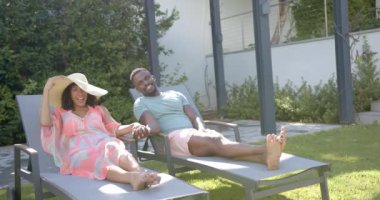 Dışarıda dinlenen, Afro-Amerikan çift el ele tutuşup havuz kenarında uzandılar. Yaz, tatil, rahatlama, rahatlık, romantizm, yaşam tarzı.