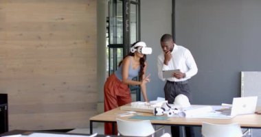 VR kulaklığı, iş arkadaşı ile işbirliği yapan bir kadın ofis planlarını gözden geçiriyor, kopyalama alanı. Teknoloji, sanal gerçeklik, işbirliği, takım çalışması, planlama, yenilik