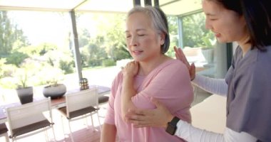 Omuz egzersizinde kıdemli Asyalı kadına yardım etmek, evde fizyoterapist. Sağlık, fizyoterapi, rehabilitasyon, yardım, terapi, fitness