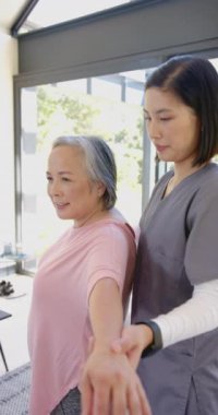 Dikey video: Fizik tedavi egzersizlerinde yaşlı kadına yardım etmek, bakıcı gülümsemesi ve destek vermek. yardım, kıdemli bakım, rehabilitasyon, sağlık hizmetleri, yaşlılar, sağlık