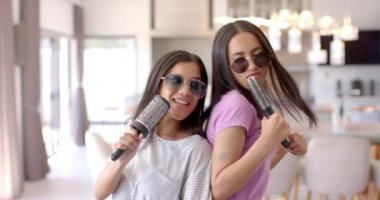 Genç kızlar mikrofonlu karaoke söylüyor, içeride birlikte vakit geçiriyorlar. Arkadaşlık, eğlence, eğlence, parti, kutlama, müzik
