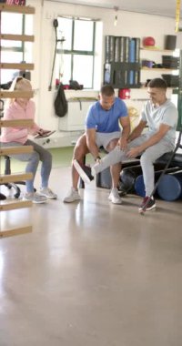 Dikey video: Protez bacaklı bir adama yardım etmek, rehabilitasyon merkezine yardım eden fizyoterapistler. Rehabilitasyon, fizyoterapi, sağlık, sağlık, yardım, terapi, yavaş çekim