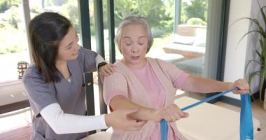 Direniş bandında kıdemli bir kadına yardım etmek, evde fizik terapist rehberliği. Fizyoterapi, rehabilitasyon, sağlık, spor, ev işleri, rehberlik.