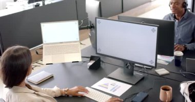 Modern ofiste çalışan, dizüstü bilgisayar ve monitör kullanan bir kadın, yakınlarda gülümseyen Afrikalı Amerikalı bir adam, kopyalama alanı. İş, takım çalışması, işbirliği, teknoloji, iş arkadaşları, profesyonel