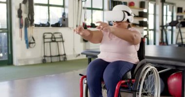 VR kulaklık kullanan, tekerlekli sandalyeli kadın terapi seansına katılıyor, kopyalama alanı. Sağlık, rehabilitasyon, fizyoterapi, teknoloji, yenilik, hasta, değişmemiş, yavaş çekim