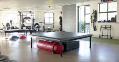 Egzersiz ekipmanlı rehabilitasyon merkezi, terapi masası ve hareketlilik yardımcıları, kopyalama alanı. Sağlık, fizik tedavi, tıbbi, klinik, iyileşme, sağIık, değişmemiş, yavaş çekim