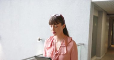 Tablet kullanıyor, pembe bluzlu kadın modern ofis ortamında çalışıyor, kopyalama alanı. Teknoloji, iş, profesyonel, üretkenlik, şirket, çalışma alanı