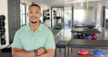 Ayak egzersizlerine yardım eden adam, rehabilitasyon salonunda paralel barlar kullanan başka bir adamı destekliyor. Rehabilitasyon, fizyoterapi, sağlık, terapi, eğitim, iyileşme, değişmemiş, yavaş çekim