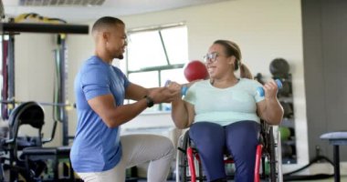 Tekerlekli sandalyede felçli bir kadına yardım etmek, rehabilitasyonda halterli bir terapiste rehberlik etmek. Rehabilitasyon, fizyoterapi, sağlık, terapi, güç, destek, değişmemiş, yavaş çekim