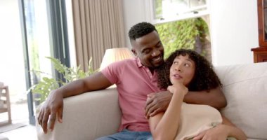 Kanepede dinlenen, gülümseyen ve evde birlikte güzel vakit geçiren bir çift. Rahatlama, birliktelik, mutluluk, bağlanma, boş zaman, yakınlık