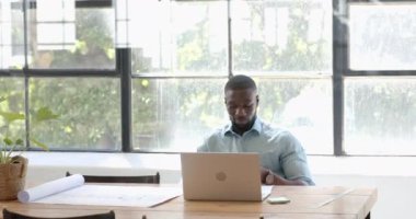 Parlak ofis ortamında dizüstü bilgisayarda çalışan gülümseyen bir iş adamı. Girişimci, çalışma alanı, üretkenlik, profesyonel, kurumsal, teknoloji