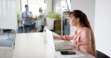 Ofiste çalışan, dizüstü bilgisayar kullanan ve not defterine yazan bir kadın, kopyalama alanı. İş, işyeri, üretkenlik, meslek ve teknoloji