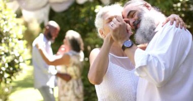 Açık hava düğününde yakın dans eden, kıdemli gelin ve damat birlikte romantik anın tadını çıkarıyorlar. Romantizm, aşk, yaşlılık, yakınlık, mutluluk, günbatımı
