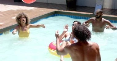 Havuzda dinlenirken, çeşitli arkadaşlar plaj topuyla oynuyorlar ve yaz gününün tadını çıkarıyorlar. Tatil, boş zaman, eğlence, yüzme, keyif, açık hava