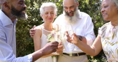 Açık hava düğününde kutlama, son sınıf arkadaşları şampanya kadehleriyle kadeh kaldırma, birlikte gülümseme. Kutlama, dostluk, yaşlılar, gülümseme, mutluluk, eğlence