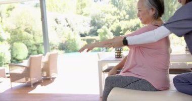 Üst düzey Asyalı kadına omuz egzersizlerinde yardım etmek, evde bakım sağlayan fizyoterapist. Sağlık, rehabilitasyon, fizyoterapi, yardım, yaşlılar, terapi