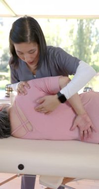 Dikey video: Fizyoterapist terapi masasında omuz egzersizi yapan yaşlı kadına yardım ediyor. Sağlık, rehabilitasyon, fizik tedavi, yaşlılık, sağlık, rehabilitasyon