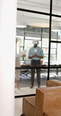 Dikey video: VR kulaklığı kullanan meslektaşlar, modern ofis ortamında projeyi tartışıyor. Teknoloji, işbirliği, takım çalışması, yenilik, iletişim, iş