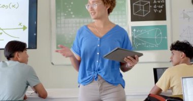 Matematik öğretmenliği, elinde tablet olan öğretmen ve lisedeki öğrencilere kavramları açıklamak. Eğitim, sınıf, öğrenme, teknoloji, matematik, öğretim