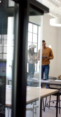 Dikey video: VR kulaklığı kullanan iş arkadaşları, modern ofis ortamında projeyi tartışıyor. Teknoloji, yenilik, takım çalışması, sanal gerçeklik, işbirliği, iş toplantısı