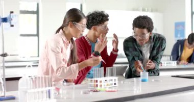 Lisedeki laboratuvarda gençler deney tüpleri ve deney tüpleriyle kimya deneyi yapıyorlar. Bilim, öğrenciler, eğitim, öğrenme, takım çalışması, güvenlik