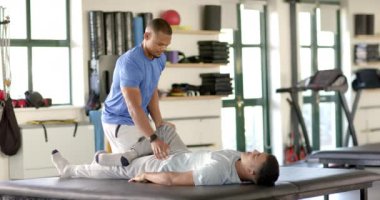 Bacak egzersizi yapan bir adama yardım, rehabilitasyon merkezinde fizik tedavi. fizyoterapi, sağlık, tıbbi, terapi, iyileşme, destek, değişmemiş, yavaş çekim