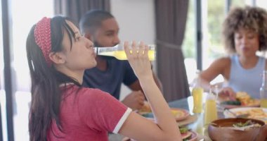 Çeşitli arkadaşlar yemekten hoşlanıyor, kadın gazoz içiyor, diğerleri yiyip sohbet ediyor. Yemek, sosyalleşme, yemek, toplanma, kutlama, eğlence