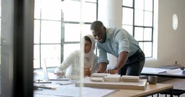 Mimari projede işbirliği, ofiste dizüstü bilgisayar ve model kullanan meslektaşlar. Takım çalışması, işbirliği, mimari, tasarım, teknoloji, beyin fırtınası