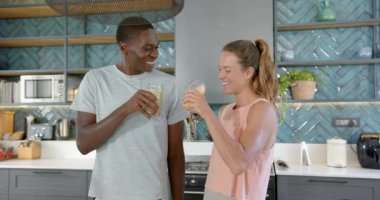 Çeşitli çiftler modern mutfakta meyve suyu içiyorlar. Kadın uzun sarı saçlı, adam gri gömlekli, değişmemiş, ağır çekimde.