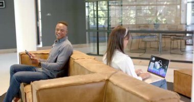 Laptop ve tablet üzerinde çalışan iş arkadaşları modern ofiste iş birliği yapıyorlar. İşbirliği, takım çalışması, teknoloji, dijital, üretkenlik, çalışma alanı