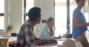 Lisedeki gençler dizüstü bilgisayar kullanıyor ve sınıf ortamında konuşuyorlar. Eğitim, teknoloji, öğrenim, öğrenim, öğrenciler, dijital