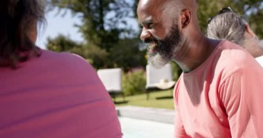 Güler yüzlü adam güneşli bahçede arkadaşlarıyla dışarıda konuşmaktan zevk alıyor. Güneş ışığı, mutluluk, açık hava, boş zaman, bağ, rahatlama.