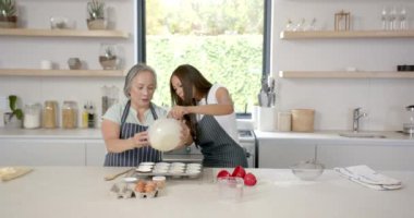 Kek pişirmek, Asyalı büyükanne ve torunun mutfakta hamuru tepsiye koyması. Aile, yemek pişirme, kaynaşma, eğlence, çok nesilli