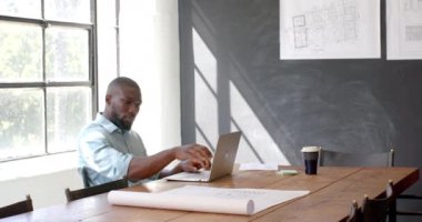 Tasarımlar üzerinde çalışan ve modern ofiste dizüstü bilgisayar kullanan bir mimar. Mimari, tasarım, yaratıcılık, teknoloji, planlama, çalışma alanı