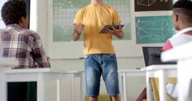 Lisedeyken, Asyalı erkek öğrenci elinde tablet tutuyordu ve sınıfta öğrencileri tanıtıyordu. Eğitim, öğrenim, teknoloji, eğitim, danışmanlık, akademik