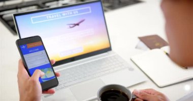 İnternetten seyahat rezervasyonu, akıllı telefon ve laptop kullanan bir adam kahve içerken. teknoloji, gezinme, planlama, dijital, gündelik, rahatlama