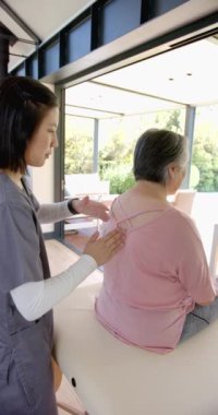 Dikey video: Fizyoterapist evde terapi seansında yaşlı kadına omuz masajı yapıyor. Rehabilitasyon, sağlık, sağlık, tedavi, fizyoterapi, rahatlama