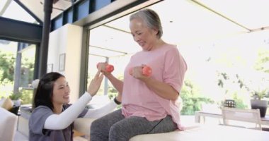 Halterli yaşlı Asyalı kadına yardım etmek, fizyoterapist ev egzersizi sırasında cesaret vermek. Egzersiz, rehabilitasyon, fizyoterapi, sağlık, spor, eğitim