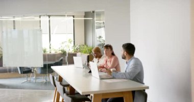 Modern ofiste işbirliği yapmak, çok ırklı meslektaşlar dizüstü bilgisayar kullanmak, proje fikirlerini tartışmak. Takım çalışması, işbirliği, beyin fırtınası, teknoloji, işyeri, iş dünyası