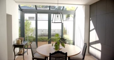 Yuvarlak masa ve sandalyeli yemek odası, büyük pencerelerden süzülen güneş ışığı, kopyalama alanı. İç mekan, ev, mobilya, minimalist, ferah, parlak