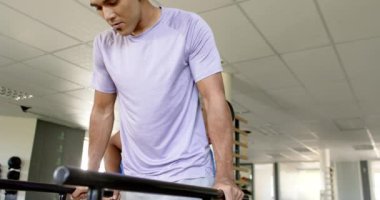 Rehabilitasyonda terapistin yardımıyla paralel barlar kullanan bir adam. Fizyoterapist, fizyoterapi, sağlık, sağlık, iyileşme, egzersiz, değişmemiş, yavaş çekim