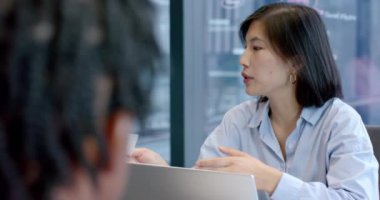 Elinde kağıt tutan ve dizüstü bilgisayar kullanan bir kadın, iş arkadaşlarıyla ofiste iş tartışan bir kadın. İşbirliği, iş, takım çalışması, iş arkadaşları, toplantı, iletişim