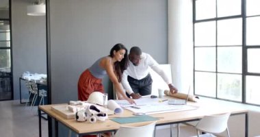 Mimari planlar üzerinde işbirliği yapan, çeşitli iş arkadaşları modern ofiste projeyi tartışıyor. İşbirliği, takım çalışması, mimari, planlama, iş toplantısı, tartışma