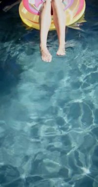 Dikey video: Havuzda dinlenmek, genç kızların ayaklarını suya daldırmak, yaz gününün tadını çıkarmak. Rahatlama, tatil, rahatlama, yüzme, havuz kenarı, ferahlatıcı.