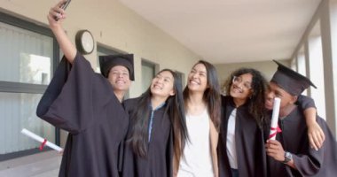 Çeşitli mezunlar başarılarını kutluyor. Liseden yeni mezun olmalarını simgeleyen kep ve cübbeler giyiyorlar..